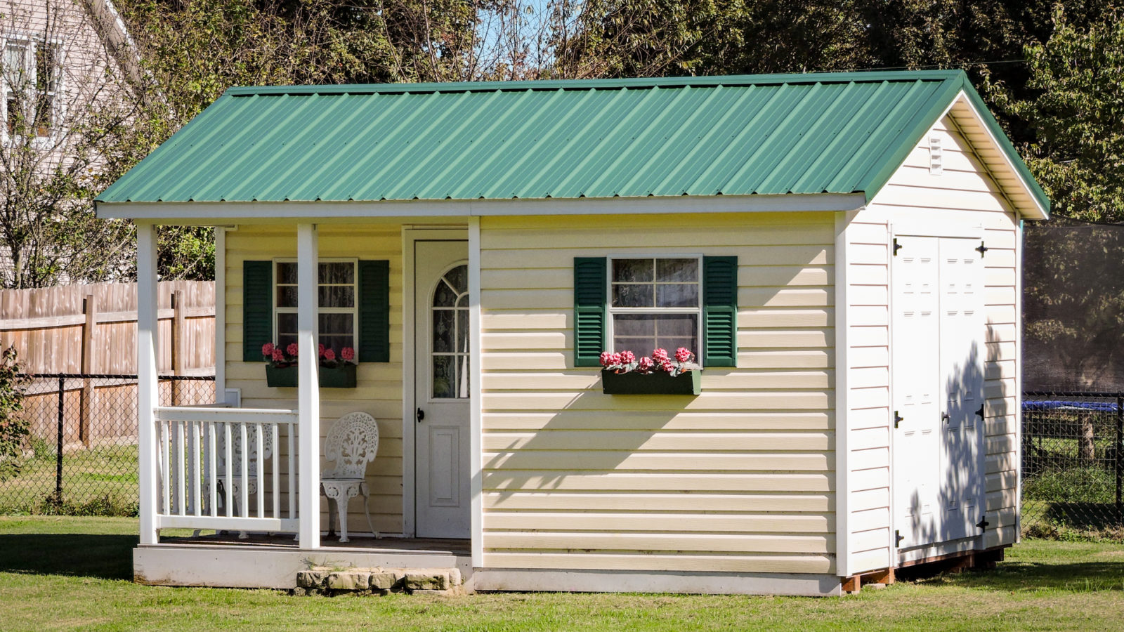 exterior of green-roofed shed with porch for sale