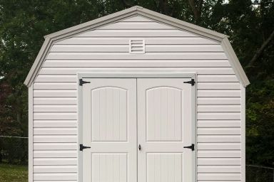 A portable building in Kentucky with vinyl siding and double doors on a concrete foundation