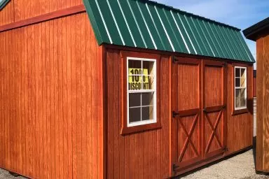 A portable building in Kentucky with wood siding and a green metal roof