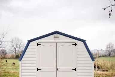 A portable building in Tennessee with vinyl siding and a blue metal roof