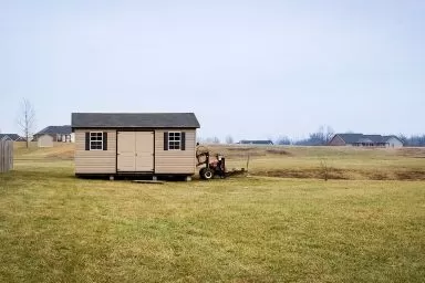 A shed being delivered in Kentucky with vinyl siding and a shingle roof