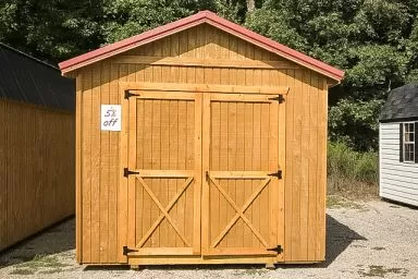 A discounted shed in Tennessee with wooden siding and a red metal roof