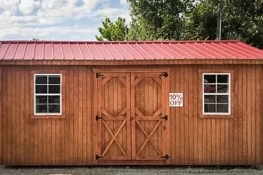 A discounted shed in Tennessee with wooden siding and a red metal roof