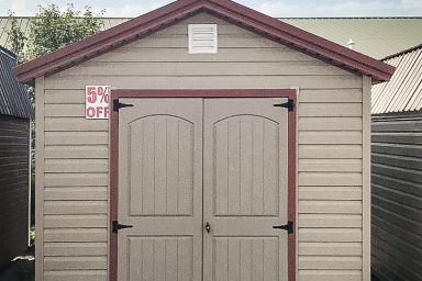 A discounted garden shed in Kentucky with vinyl siding, double doors, and a red metal roof