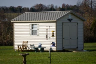 A storage shed in Kentucky with vinyl siding, double doors, and a metal roof