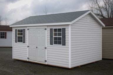 A storage shed in Kentucky with white vinyl siding, double doors, and a shingle roof