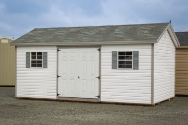 A storage shed in Kentucky with vinyl siding, double doors, and windows with shutters