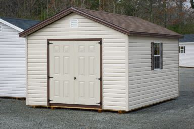 A storage shed in Kentucky with vinyl siding, double doors, and a brown shingle roof