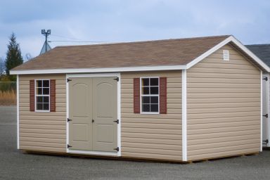 A storage shed in Kentucky with brown vinyl siding, double doors, and windows with shutters
