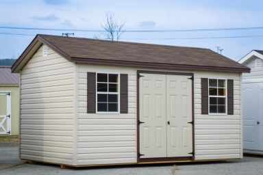 A storage shed in Kentucky with vinyl siding, double doors, and windows with brown shutters