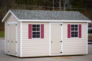 A storage shed in Kentucky with vinyl siding, double doors, and windows with red shutters