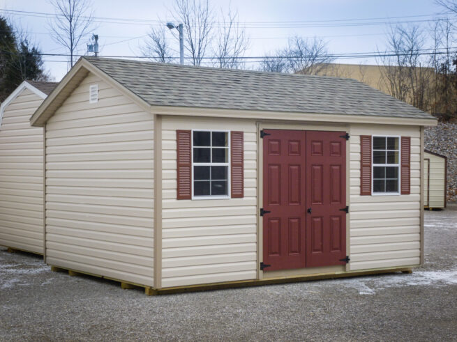 A storage shed in Kentucky with vinyl siding, brown double doors, and windows with shutters for sale in KY and TN