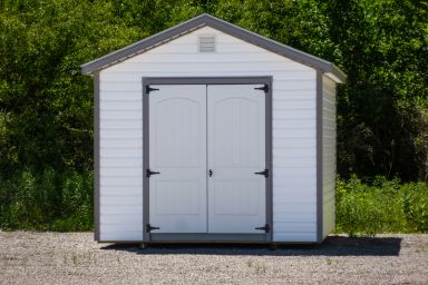 A storage shed in Tennessee with white vinyl siding and double doors