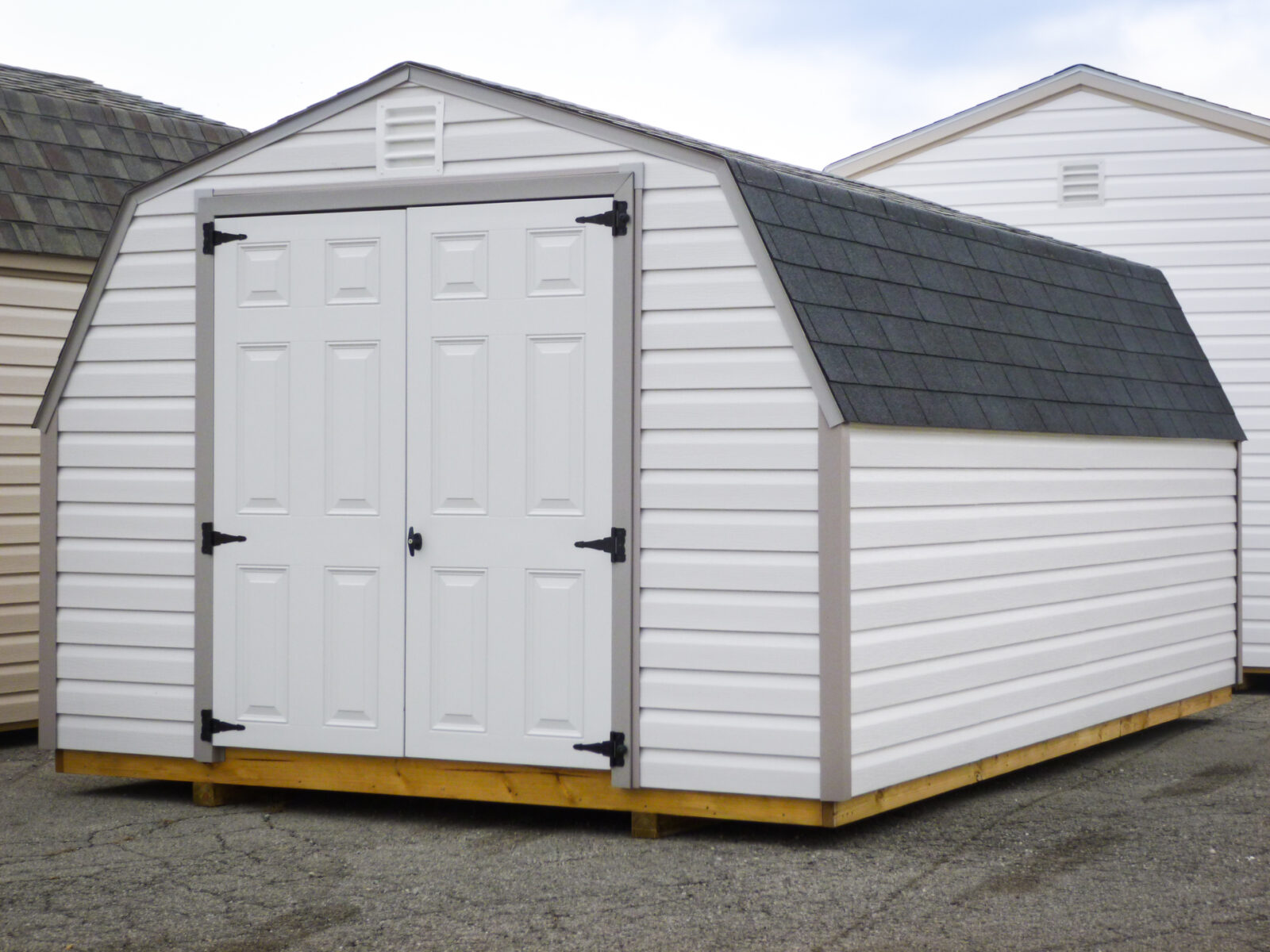 A portable shed in Kentucky with white vinyl siding, a shingle roof, and double doors