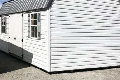 An outdoor shed in Tennessee with white vinyl siding, double doors, and a metal roof