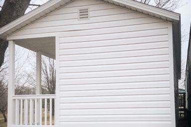 A portable cabin for sale in Tennessee with vinyl siding and a porch