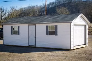 A garage shed in Kentucky with white vinyl siding and two windows with shutters